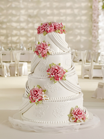 beige wedding cake with roses and ribbons close-up