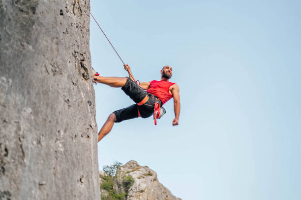 istock Athletic man climbs a rock with a rope 1692382454