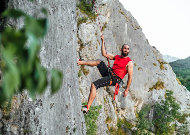 istock Athletic man climbs a rock with a rope 1692382782