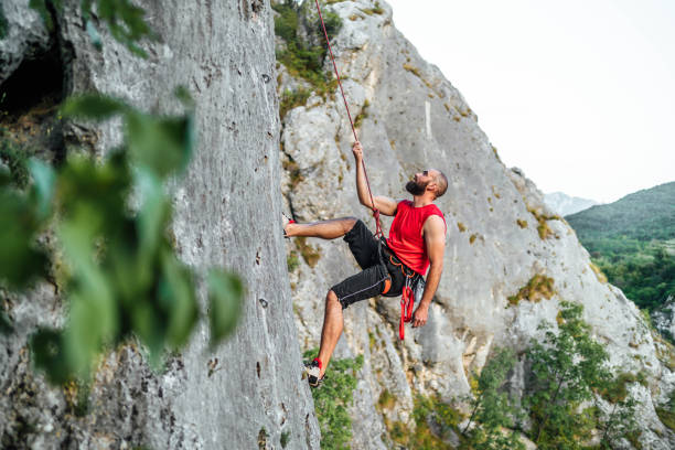 istock Athletic man climbs a rock with a rope 1692382796