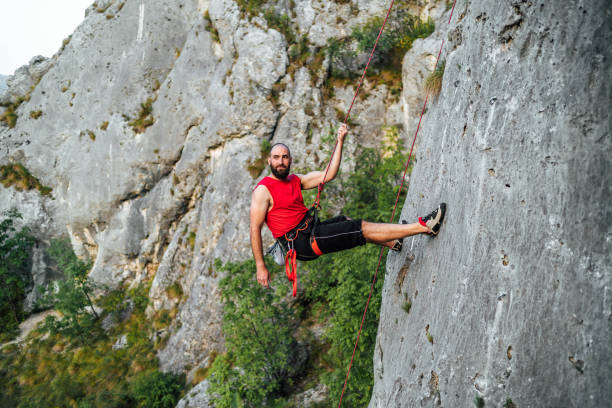 istock Athletic man climbs a rock with a rope 1692382808