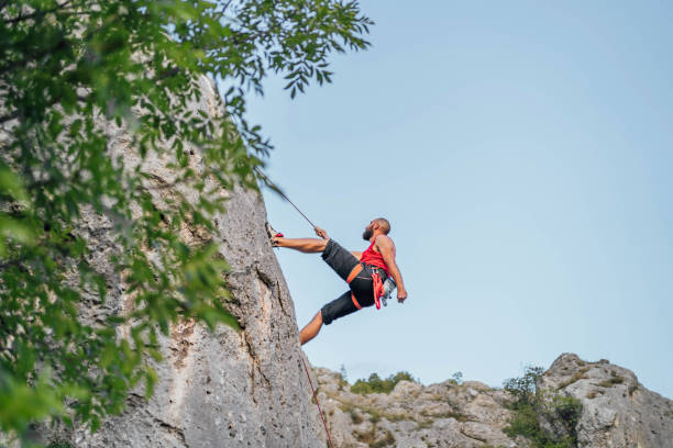 istock Athletic man climbs a rock with a rope 1692383335