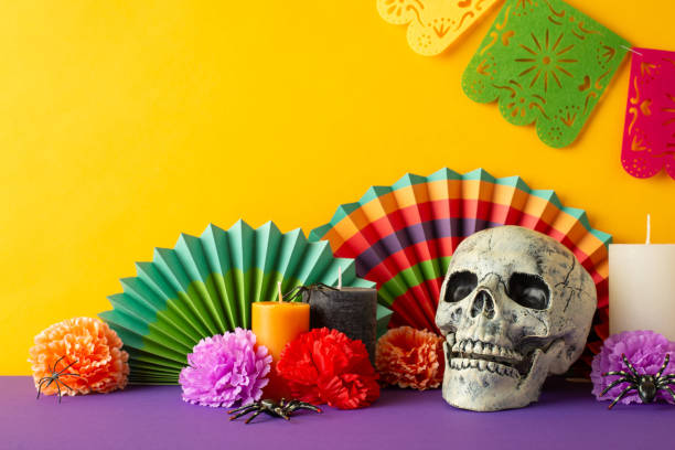istock Vibrant Day of the Dead-inspired side view setup with a violet table adorned with calavera skull, colorful fans, flowers, candles, spiders, and festive flag garlands against a yellow wall background 1692386387