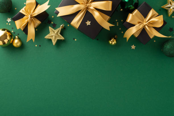 istock Celebratory gift arrangement: Top view of opulent black gift boxes featuring gold bows, accompanied by gold and green baubles, star embellishments, confetti on green surface for your message or advert 1692386478
