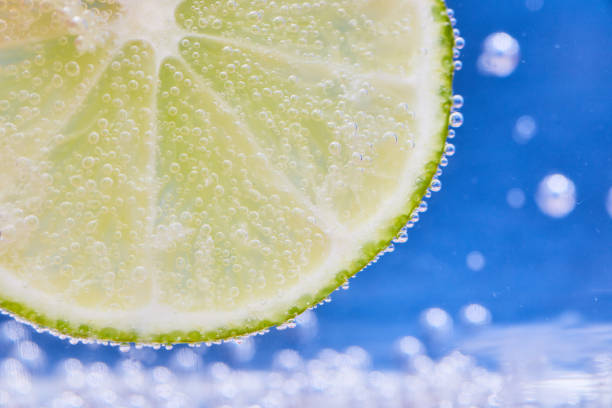 istock Green lime slice with silvery bubbles and blue background 1692387710