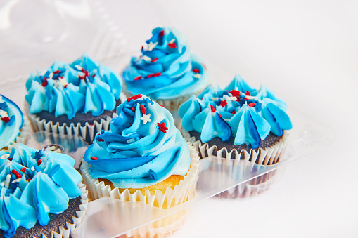 Image of Patriotic Fourth of July cupcakes with red white and blue tops in plastic container
