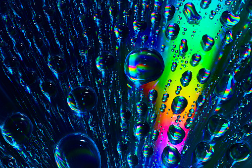 Image of Upward flowing fizzy bubbles with a ray of rainbow colored burst in abstract background asset