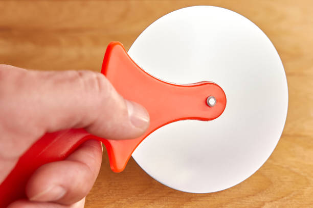 A man holds a knife for cutting pizza.