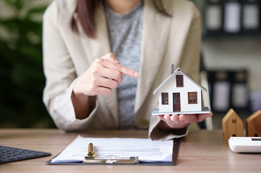 female real estate agent offers home equity loans to clients with loan calculations and home sales contracts in the office. Real estate and insurance buying savings concept