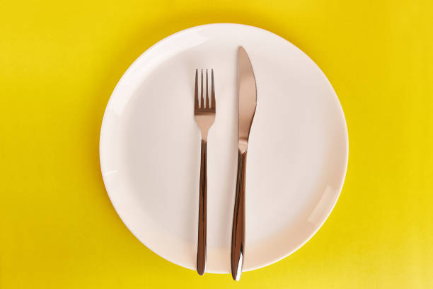istock White plate with fork and knife on gray background. 1692409804