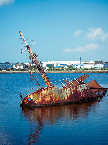 Old rusty hull of boat listing in the water at Alfred dock Birkenhead Wirral UK