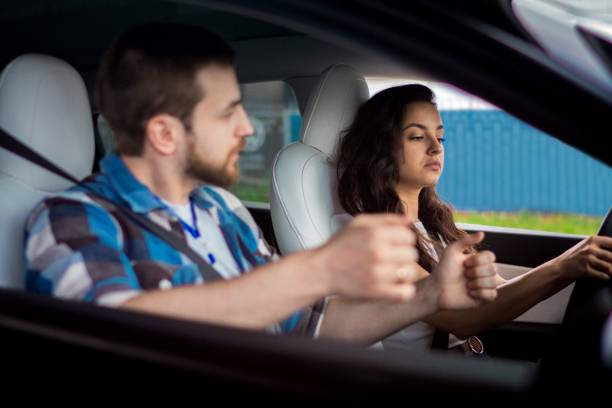 istock Male instructor controlling and checking during studying in school. Young woman driving and looking at the road. Driving test, driver courses, exam concept 1692428513