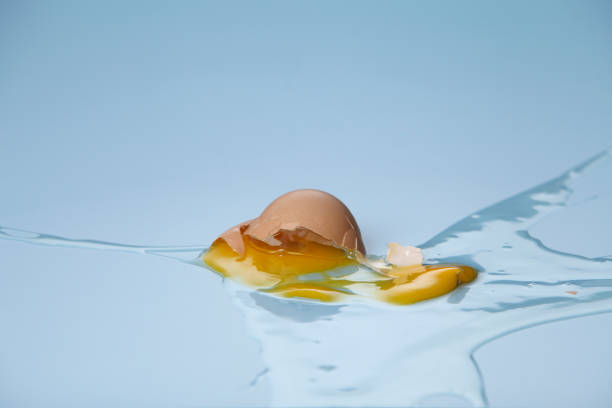 istock cracked egg shell and spilled egg white and yolk on blue background 1692441282