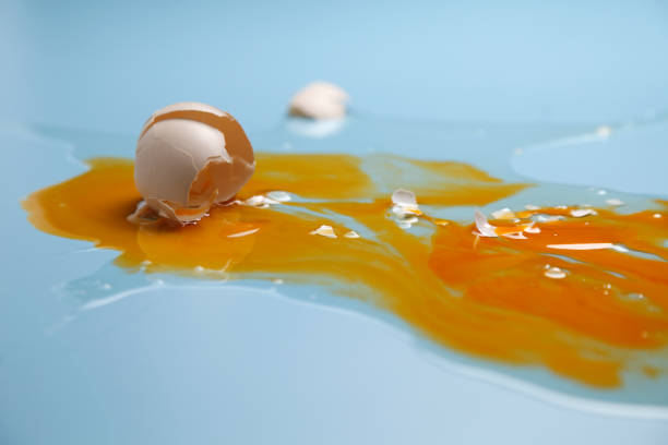 istock cracked egg shell and spilled egg white and yolk on blue background 1692442439