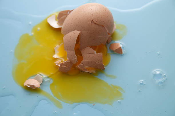 istock cracked egg shell and spilled egg white and yolk on blue background 1692442457