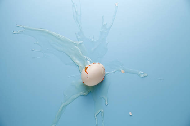 istock cracked egg shell and spilled egg white and yolk on blue background 1692442458