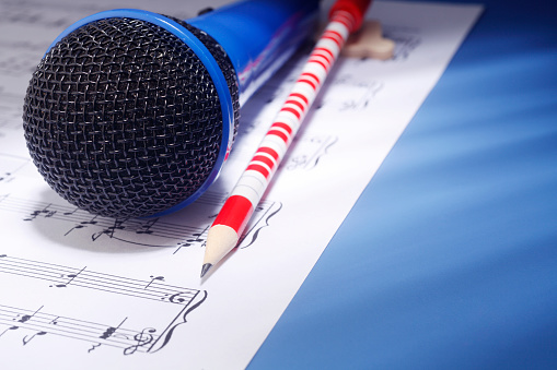 Microphone with music sheet and pencil.