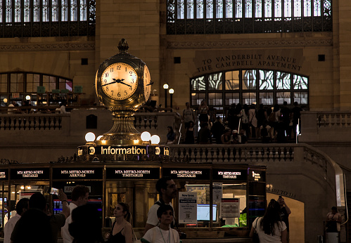 New York, NY - Aug 7 2023: Commuters pass clock at Grand Central Terminal on 42nd street in Manhattan.  Busy urban train station.