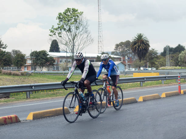 dos ciclistas circulando por una carretera durante una mañana calurosa. deporte y bienestar. - speed sports race track cycling vitality fotografías e imágenes de stock