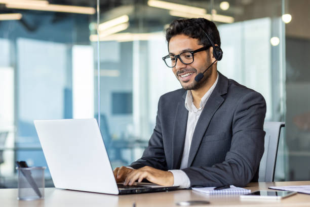 istock Young successful man at workplace with headset phone typing on laptop keyboard, customer support worker for online buyers inside office, hispanic helping and consulting customers 1692546038