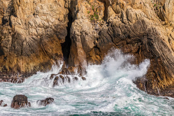 Ocean wave breaking against rocky cliff. Ocean wave breaking against rocky cliff at Point Lobos Nature Preserve, Monterey, California. point lobos state reserve stock pictures, royalty-free photos & images