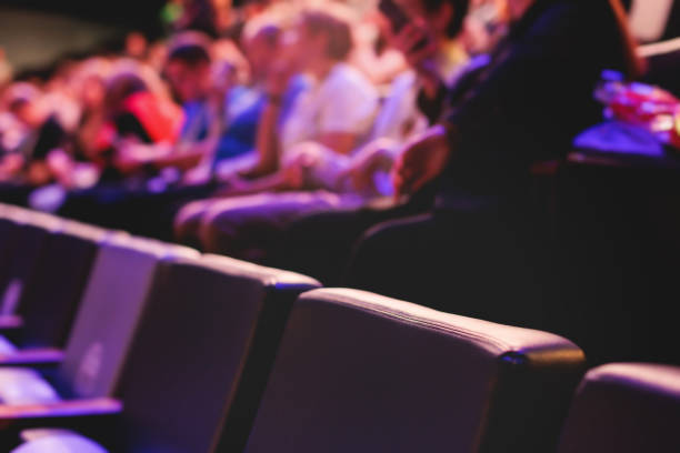 istock Audience at the modern conference hall listens to panel discussion, people on a congress together listen to speaker on stage at convention, business seminar, amphitheater venue for congress 1692553255