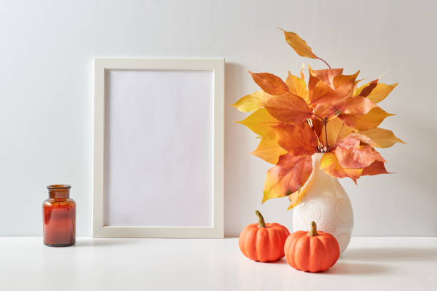 istock Mockup with a white frame and colorful autumn leaves in a vase on a light background. Empty poster frame mockup for presentation design, text, lettering 1692562885