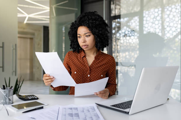 istock Sad and disappointed businesswoman inside office at workplace looking at documents papers financial reports, african american female worker on paper work depressed unhappy with financial achievements 1692576283