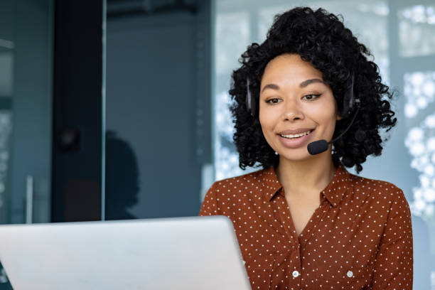 istock Young beautiful office worker using headset microphone and laptop for video call, businesswoman typing on keyboard smiling satisfied with achievement results successful African American woman 1692577135