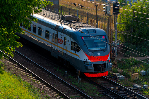 Russia, Moscow - August 06, 2022: Modern commuter rail (Moscow Central Diameters train) drives on railway tracks in a sunny summer day. Soft focus. Public transportation theme.