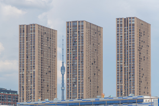 Russia, Moscow - August 07, 2022: Ostankino TV Tower is visible between modern highrise apartment buildings against overcast sky. Soft focus. Cityscape theme.