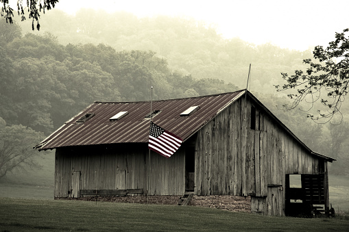 an old country barn on memorial day with its new flag at half staff