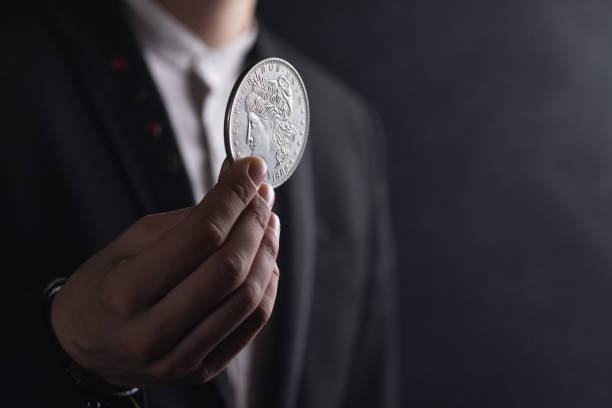 male hand with one dollar coin on dark background