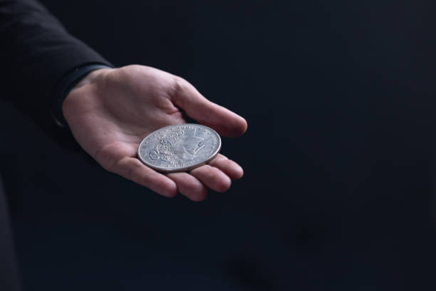 istock male hand with one dollar coin on dark background 1692595766