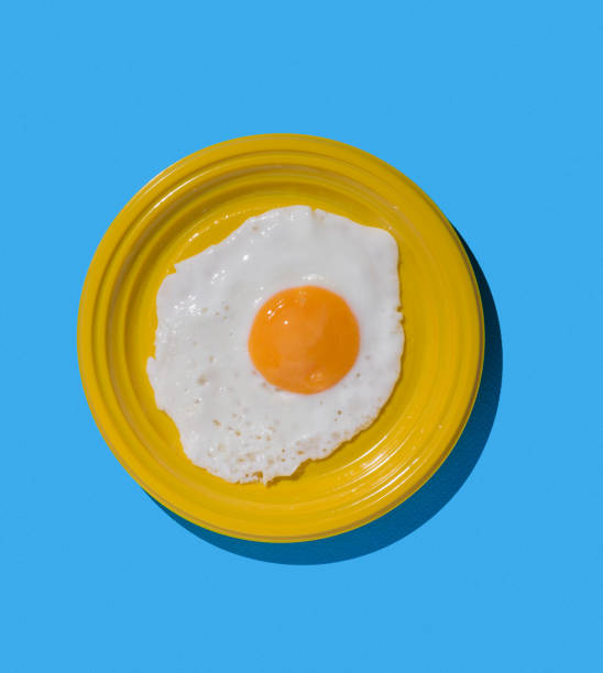 istock One fried egg on a yellow plate on a blue background. Minimal concept. A popular breakfast. 1692599067