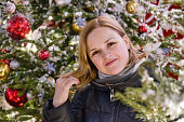 Portrait of beautiful smiling European woman on Christmas tree background. Happy woman in new year holidays.