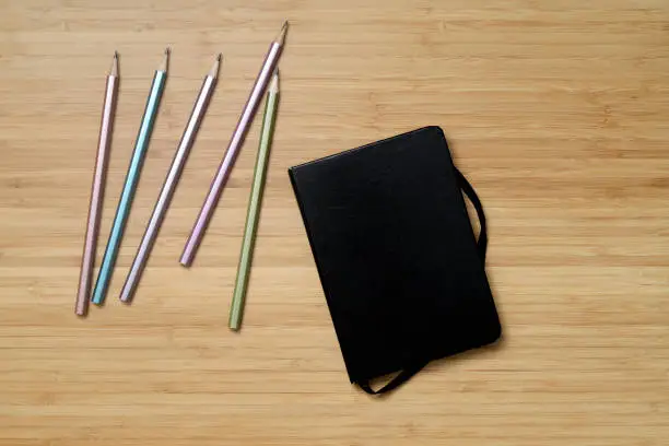 top view of various pencils on wood with notebook