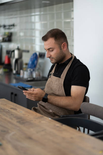 istock Artist young man wearing apron using phone 1692615173