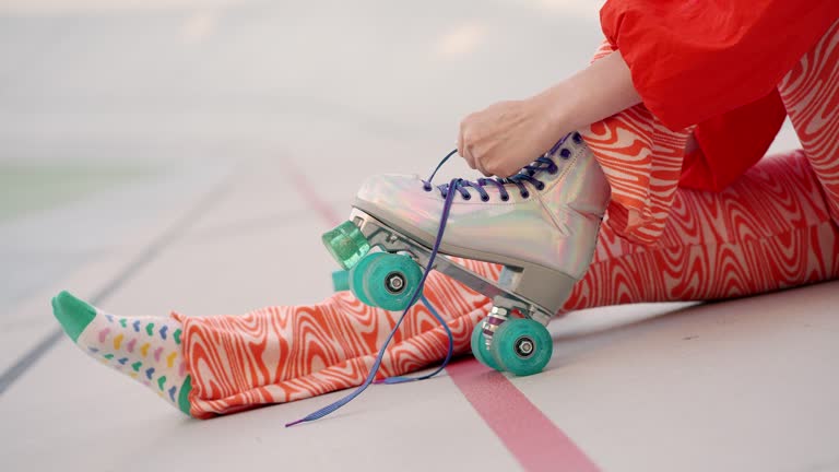 Female roller skater tying laces on pearly quad wheel boots