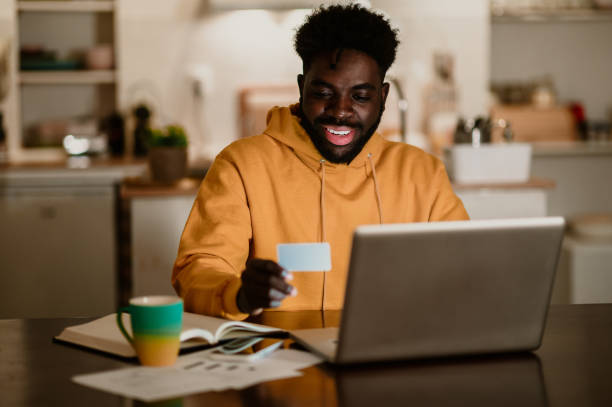 istock A happy interracial man is sitting at home at night and using a credit card 1692635448