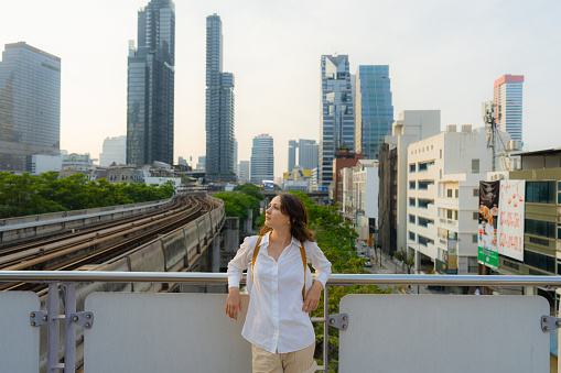 Young Caucasian woman in sunhat  standing on the background of Bangkok cityscape