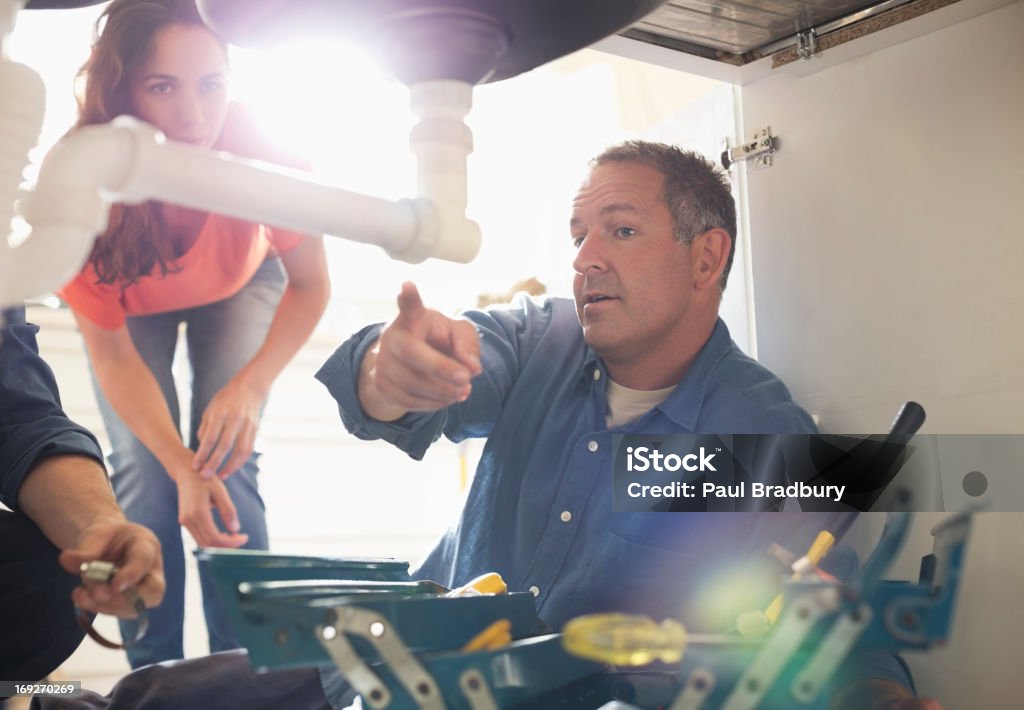 Plumbers working on pipes under sink  Plumber Stock Photo