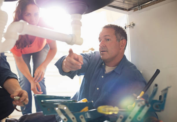 Plumbers working on pipes under sink stock photo