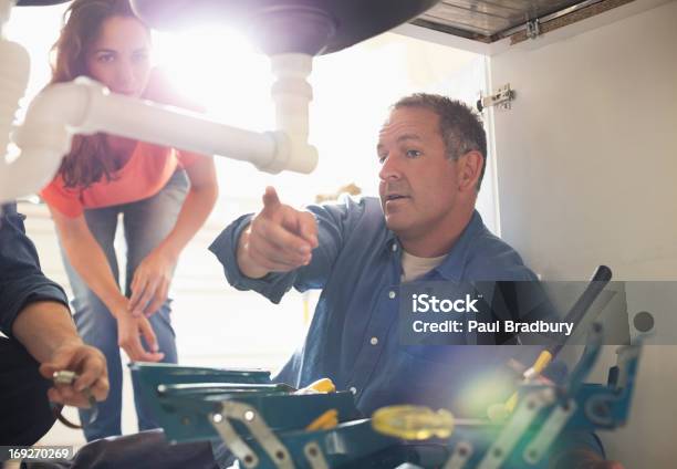Plumbers Working On Pipes Under Sink Stock Photo - Download Image Now - Plumber, Customer, Craftsperson
