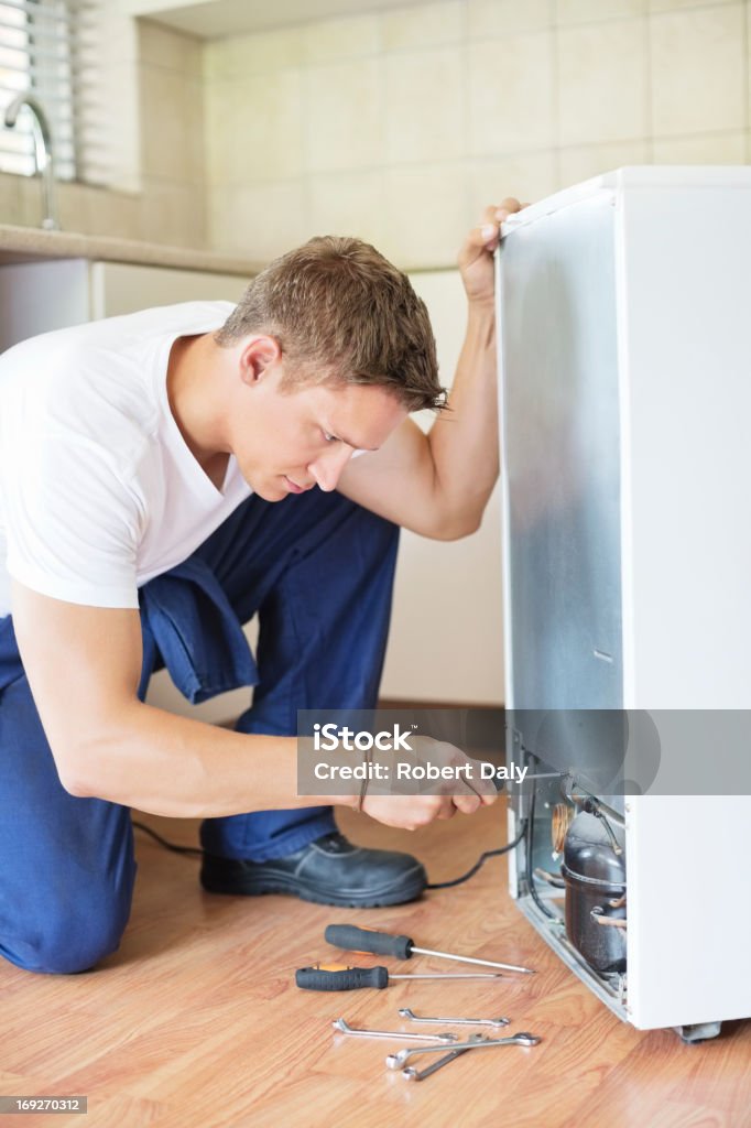 Repairman working on appliance in kitchen  25-29 Years Stock Photo