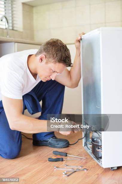 Repairman Working On Appliance In Kitchen Stock Photo - Download Image Now - 25-29 Years, Adult, Adults Only