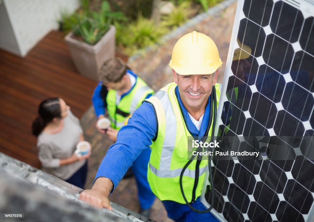 Worker installing solar panel on roof  Solar Panel Stock Photo