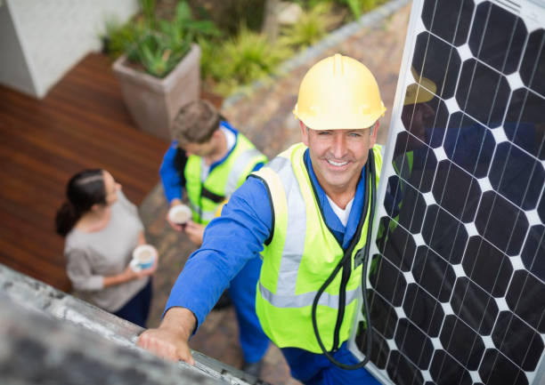 Worker installing solar panel on roof stock photo