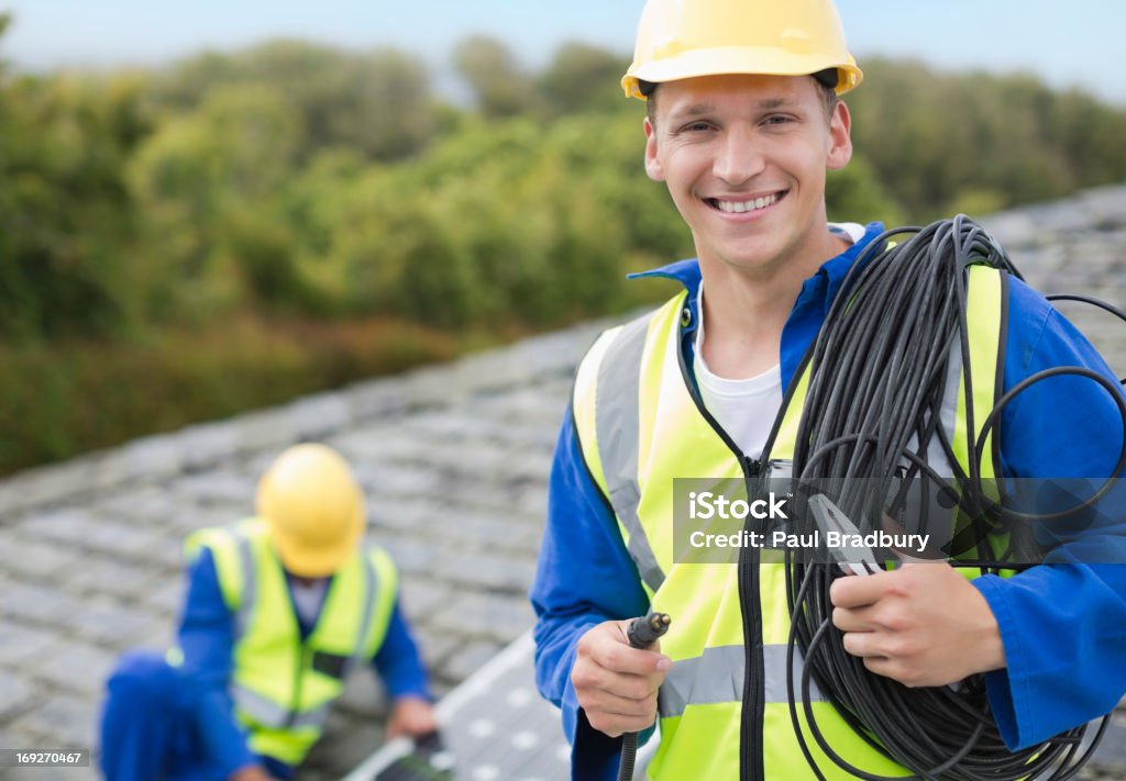 Worker smiling on rooftop  Electrician Stock Photo