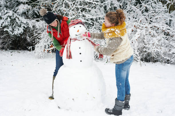 istock Mother and daughter making snowman 169270554